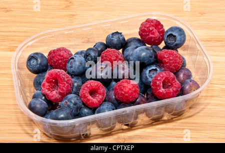 Gemischte Beeren in Kunststoff-Box auf Bambus-Hintergrund Stockfoto