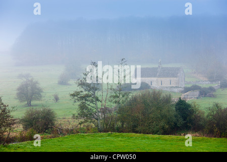 Nebligen Szene und St. Oswald Kirche, einer abgelegenen Kapelle auf einem Feld am Widford in der Nähe von Burford in Cotswolds, Oxfordshire, Vereinigtes Königreich Stockfoto