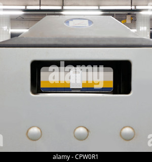 Mülleimer in einem Bahnhof mit einem vorbeifahrenden Zug Stockfoto