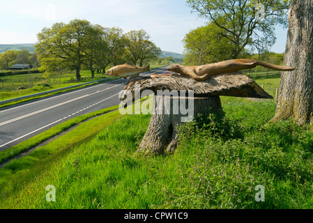 Hölzerne Otter jagen Forellen Skulptur über eine neue verbesserte Ausschnitt der A470 in der Nähe von Newbridge on Wye, Powys. Stockfoto