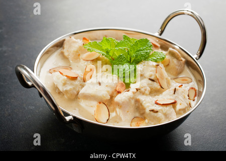 Mild und cremig Chicken Korma, in eine Schüssel Balti, garniert mit Minze, Mandeln und geröstetem Kreuzkümmel Samen auf einem dunklen Hintergrund. Stockfoto
