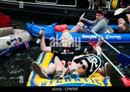 Königin Jubillegal Flottille schwimmende Partei. Party Gänger sind Piraten und Mann in einer Königin-Maske mit Bürstenhalter Rudern. Stockfoto