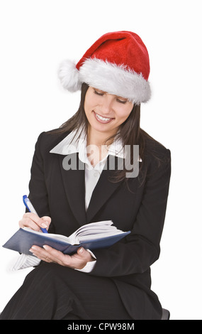 Junge Frau mit Nikolausmütze Notizen über die gewünschte Weihnachtsgeschenke. Stockfoto