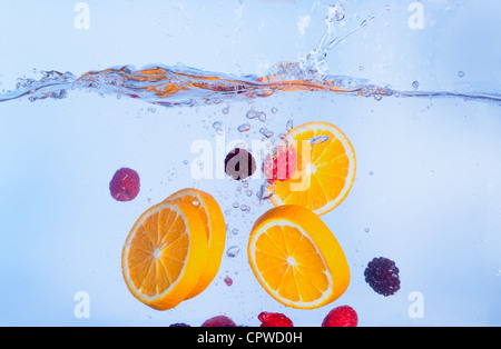 Fresh Fruit Falls unter Wasser mit einem Spritzer, blauer Hintergrund Stockfoto