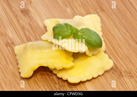 Leere Ravioli dekoriert mit Basilikum auf hölzernen Hintergrund Stockfoto