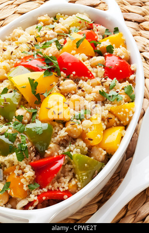 Couscous mit Kichererbsen, rote, grüne und gelbe Paprika, Zwiebeln, Kümmel und Petersilie, zubereitet mit Olivenöl extra vergine. Stockfoto