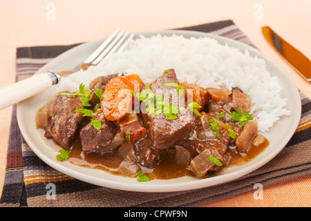 Französisch Rindfleisch Eintopf in Rotwein, auf einem Teller mit Reis. Bekannt als Daube de Boeuf Provencal. Stockfoto