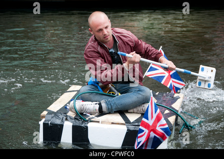 Queen es Jubillegal Flottille schwimmende Party, Regent es Canal. Mann auf hausgemachte Floß Paddeln mit Stock-mop Stockfoto