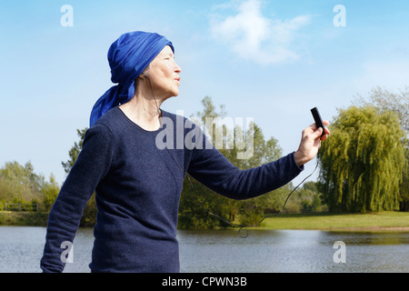 Ältere Frau mit MP3-Player von See, Seitenansicht. Stockfoto