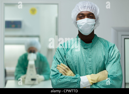 Porträt des Mannes, die Arbeit im Forschungszentrum Biotechnologie mit Frau auf der Suche durch Mikroskop im Hintergrund Stockfoto