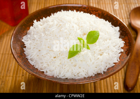 Eine Schüssel von perfekt gekocht, plain Basmati-Reis in eine Schüssel asiatischen Stil mit einer Garnierung von Thai-Basilikum. Stockfoto