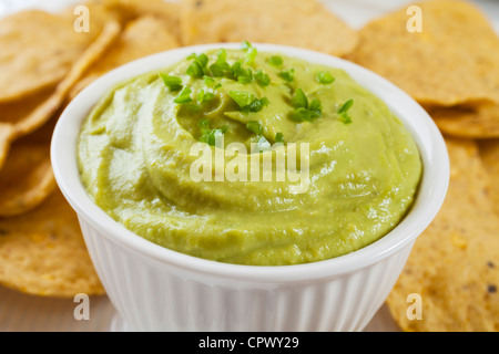 Guacamole garniert mit frischen grünen Chili mit Mais-Chips zum Dippen. Flache DF, Fokus auf Chili. Stockfoto