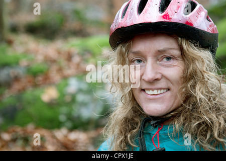 Reife Frau mit Fahrradhelm im Wald Stockfoto