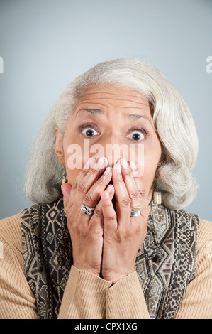 Porträt von senior Frau den Mund mit den Händen in studio Stockfoto