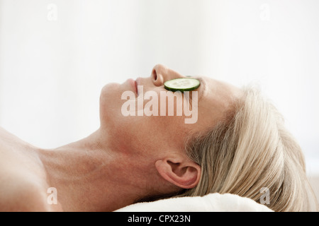 Reife Frau mit Gurkenscheiben über Augen entspannen Stockfoto