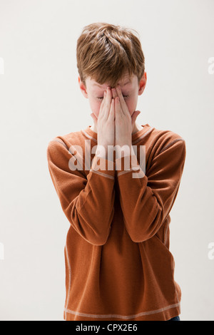 Junge im braunen Pullover Augen reiben, Studio gedreht Stockfoto