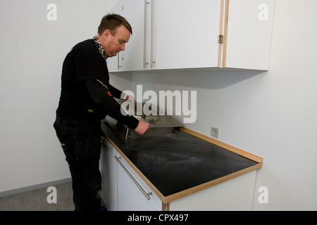 Heizungs- und Sanitär-Techniker installiert eine Küchenspüle Stockfoto
