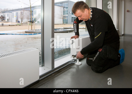 Heizungs- und Sanitär-Techniker einen Heizkörper anschließen Stockfoto