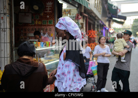 Asia CHINA Guangzhou , fast 100,000 afrikanische Händler kaufen und versenden Textilien und andere Waren von hier nach afrika, Einkaufsstraße, afrikanische Frau und chinesische Familie mit einem Kind Stockfoto