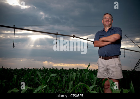 Weißer Farmer steht lächelnd in ein Feld von Pflanzen mit seine Arme gekreuzt Stockfoto