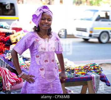 Straßenhändler in lila Kleid lächelt in die Kamera Stockfoto