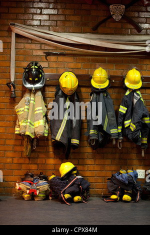 Feuerwehr-Uniformen, die an einer Wand aufhängen Stockfoto