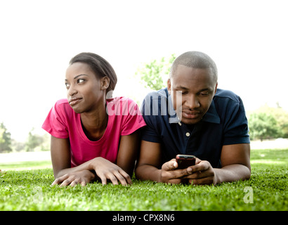 Closeup Portrait eines jungen Paares schwarz, auf dem Boden liegen, während Man mit dem Handy spielt Stockfoto