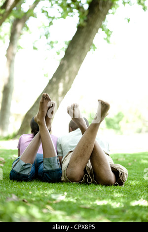 Schuss von hinten von einem jungen schwarzen paar liegen auf dem Rasen in einem Park Stockfoto