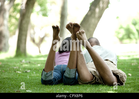 Schuss von hinten von einem jungen schwarzen paar liegen auf dem Rasen in einem Park Stockfoto