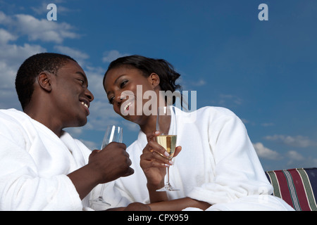 Eine afrikanische paar teilen einen intimen Moment während Roben tragen und halten Sektgläser Stockfoto