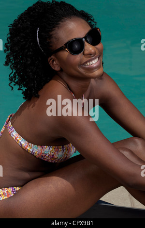 Junge schwarze Frau liegend auf einem Liegestuhl neben einem pool Stockfoto