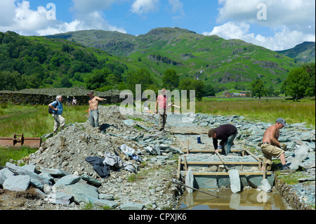 Arbeitnehmer, die einen Pfad mit Elterwater pitching grün Schiefer, in der Nähe von Easedale Tarn in Lake District National Park, Cumbria, England Stockfoto