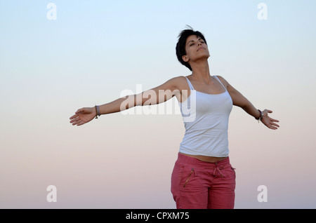 Attraktive junge Frau entspannt sich in der Natur mit weit offenen Armen Stockfoto