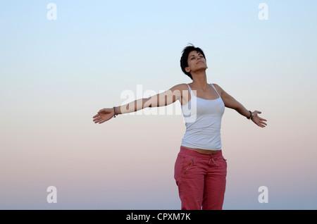 Attraktive junge Frau entspannt sich in der Natur mit weit offenen Armen Stockfoto