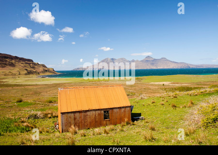 Eine alte Wellblech-Scheune am Cleadale auf der Insel Eigg, mit Blick auf die Isle of Rum, Schottland, UK. Stockfoto