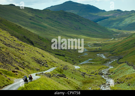 Radfahrer auf der Fahrbahn über den Wrynose Pass im Dudden Tal Teil des Lake District National Park, Cumbria, England Stockfoto