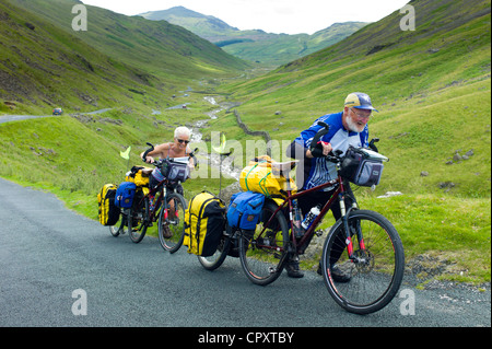 Radfahrer auf der Fahrbahn über den Wrynose Pass im Dudden Tal Teil des Lake District National Park, Cumbria, England Stockfoto