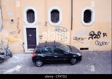 Kleine schwarze Auto vor einem Haus mit Graffiti in Rom gekennzeichnet geparkt. Stockfoto
