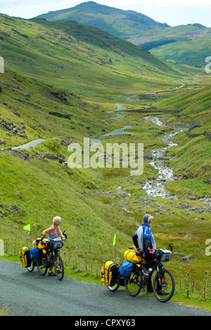 Radfahrer auf der Fahrbahn über den Wrynose Pass im Dudden Tal Teil des Lake District National Park, Cumbria, England Stockfoto