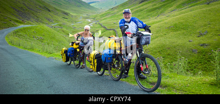 Radfahrer auf der Fahrbahn über den Wrynose Pass im Dudden Tal Teil des Lake District National Park, Cumbria, England Stockfoto