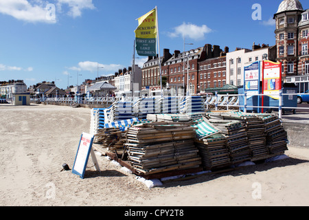 LIEGESTÜHLE GESTAPELT AM WEYMOUTH BEACH DORSET Stockfoto