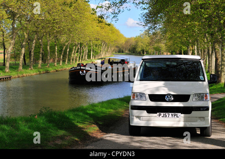 Wohnmobil fahren entlang Kanal Nebenstraße auf dem Canal du Midi in der Nähe von Castelnaudary mit Vergnügen Kanalboot in der Ferne Stockfoto