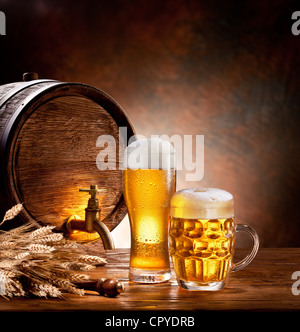 Bierfass mit Biergläsern auf einem Holztisch. Der dunkle Hintergrund. Stockfoto