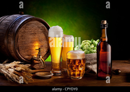 Bierfass mit Biergläsern auf einem Holztisch. Die dunkelgrünen Hintergrund. Stockfoto