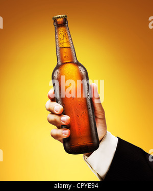 Eine Flasche Bier in die Hand eines Mannes auf einem gelben Hintergrund. Stockfoto