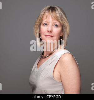 Portrait von attraktiven mittleren Alters Frau mit rätselhaften Blick auf grauem Hintergrund Stockfoto