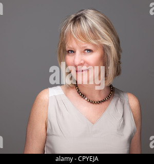 Porträt von attraktiven lächelnd elegante Reife Frau auf grauem Hintergrund Stockfoto