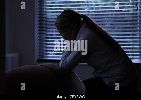 Profil von einem Mädchen mit einem Pferdeschwanz sitzen Händen bedeckte ihr Gesicht. Silhouette. Stockfoto