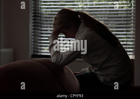 Profil von einem Mädchen mit einem Pferdeschwanz sitzen Händen bedeckte ihr Gesicht. Silhouette. Stockfoto