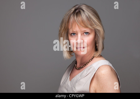 Kopf geschossen Porträt attraktive Reife Frau mit intensiven Blick auf grauem Hintergrund Stockfoto